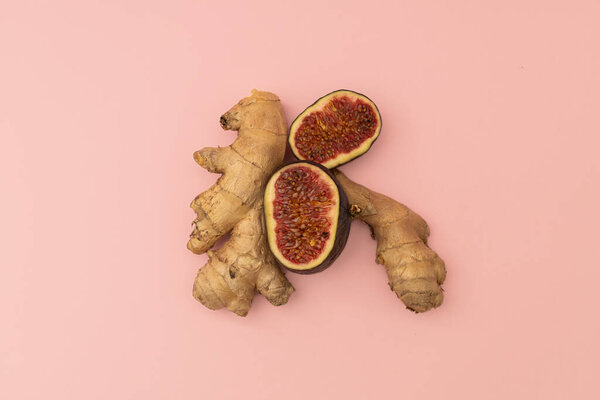 Ginger root and cut figs on a pink background