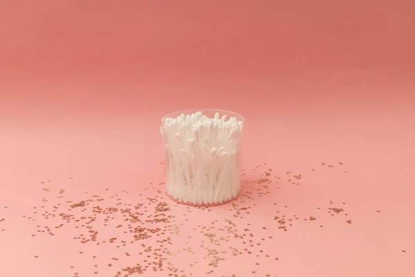 stock image Ear cotton swabs in a clear cup on a pink background