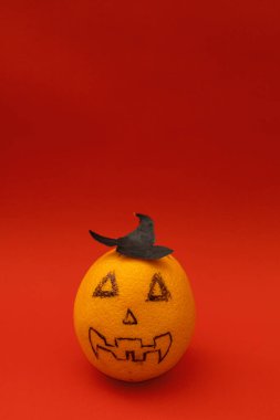 Turuncu, kırmızı arka planda Cadılar Bayramı balkabağına benziyor. Korkunç bir meyve.