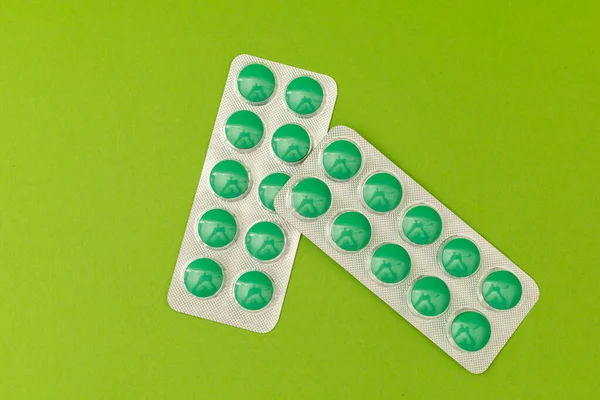 Green pills on a green background, monochrome