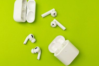 Renkli yeşil arka planda beyaz kulaklıklı kablosuz kulaklık, reklam kulaklıkları.