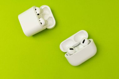 Renkli yeşil arka planda beyaz kulaklıklı kablosuz kulaklık, reklam kulaklıkları.