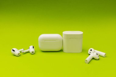 Renkli yeşil arka planda beyaz kulaklıklı kablosuz kulaklık, reklam kulaklıkları.