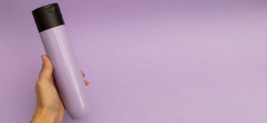 Mor arka planda şık, mor plastik bir kavanozda saç şampuanı, tek renkli eşyalar.