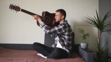 Bir adam silah taklidi yaparak gitar ateşliyor.