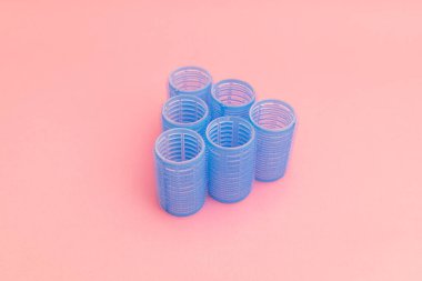 Large blue hair curlers on a bright pink background