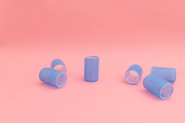 Large blue hair curlers on a bright pink background