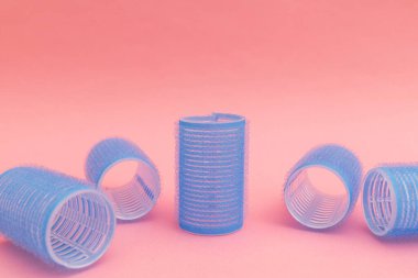 Large blue hair curlers on a bright pink background