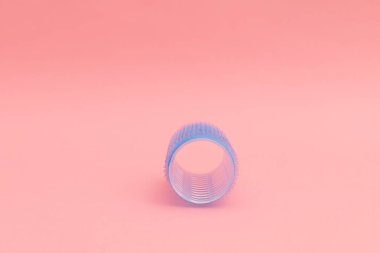 Large blue hair curlers on a bright pink background