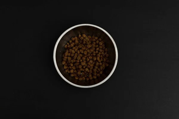 Dry dog food in an aluminum plate on a black background, dog food