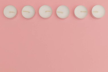 Small candles in metal jars on a pink background for use in the absence of light