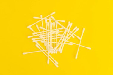 White cotton swabs on a bright yellow background
