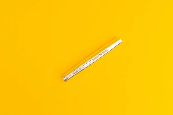 Mascara in silver package with yellow background