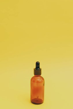 Sarı arka planda serum şişesi