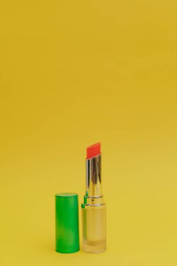 Sarı arka planda parlak yeşil şapkalı ruj.