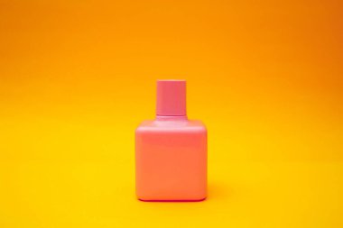 Turuncu arka planda parlak pembe bir parfüm.