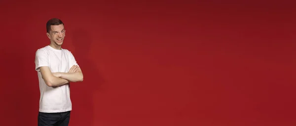 Banner, kırmızı arka planda genç bir adam kollarını göğsünde kavuşturmuş.