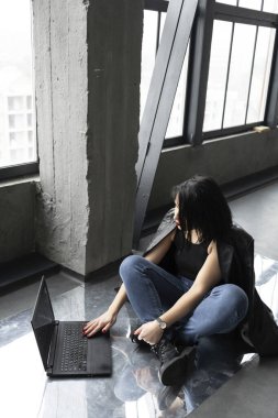 Kotlu siyah saçlı kız, dizüstü bilgisayarda yazıyor.