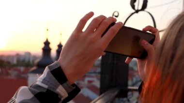 Adamın biri telefonuyla gün batımının fotoğrafını çekiyor.