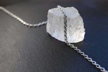 Şeffaf bir taşın üzerinde gümüş bir zincir var.