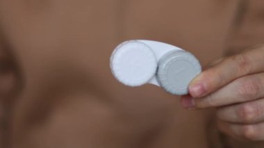 Kızın elinde kontakt lens kabı var.