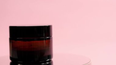 Krema kavanozu pembe bir arka planda döner.