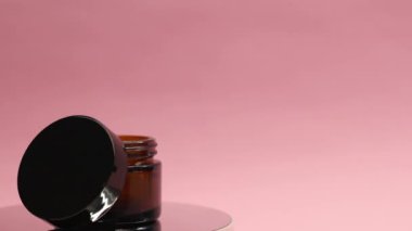 Krema kavanozu pembe bir arka planda döner. 