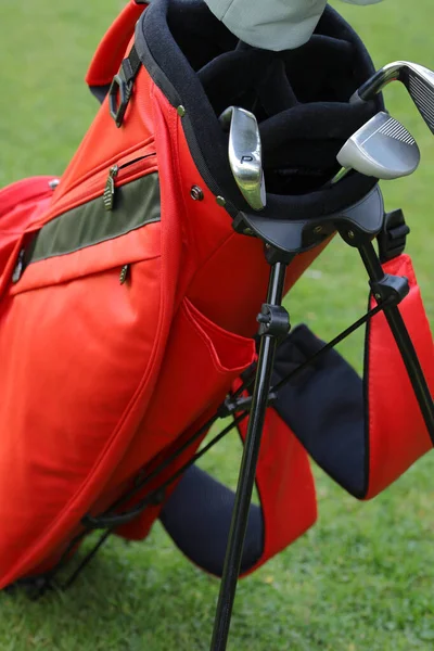 Kırmızı çantada golf sopaları, demir, golf sopası ve atış.