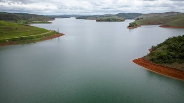 Yukarıdan bakıldığında insansız hava aracı, alçak seviyesi ve doğanın arka planıyla dolu bir baraj..
