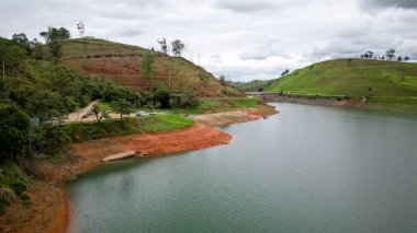 Yukarıdan bakıldığında insansız hava aracı, alçak seviyesi ve doğanın arka planıyla dolu bir baraj..