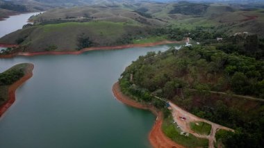 Yukarıdan bakıldığında insansız hava aracı, alçak seviyesi ve doğanın arka planıyla dolu bir baraj..