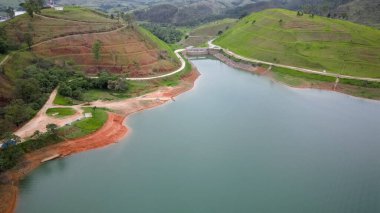 Yukarıdan bakıldığında insansız hava aracı, alçak seviyesi ve doğanın arka planıyla dolu bir baraj..