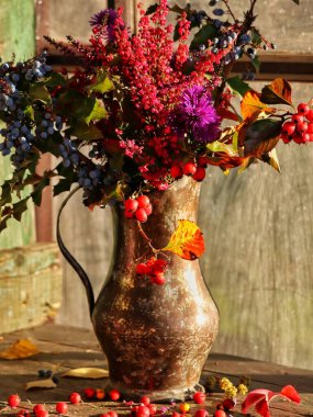 Sonbaharda vazoda çiçekler, kırsal bir ortamda dekoratif aksesuarlar ve sıcak renkler.