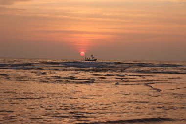 Denizde gün batımında bir teknenin silüeti - stok fotoğrafı