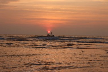 Denizde gün batımı bir teknenin silüeti, manzara fotoğrafçılığı.