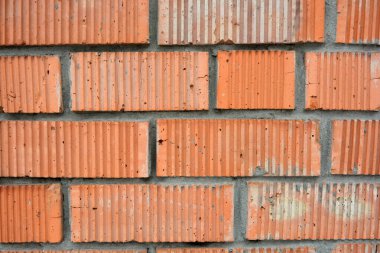 Building background, red beautiful brick wall with grooved sides, masonry of bricks and gray cement.