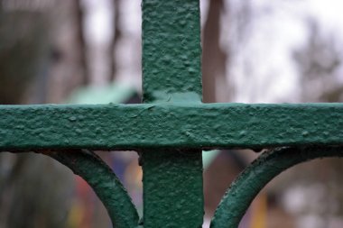 An old Soviet metal fence welded with an interesting shape, arrows and circles, painted with green paint.