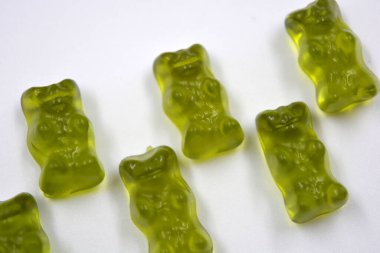 Bright children's green chewing, jelly candies in the form and in the form of colored bears are located on a white background.