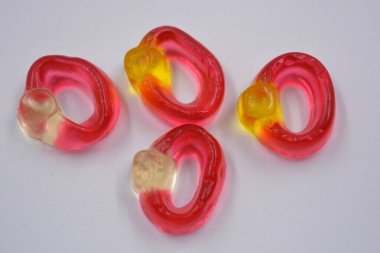 Bright children's colored chewing, jelly candies in the form and in the form of a women's wedding rings with a diamond are located on a white background.
