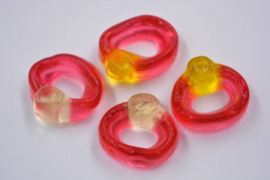 Bright children's colored chewing, jelly candies in the form and in the form of a women's wedding rings with a diamond are located on a white background.