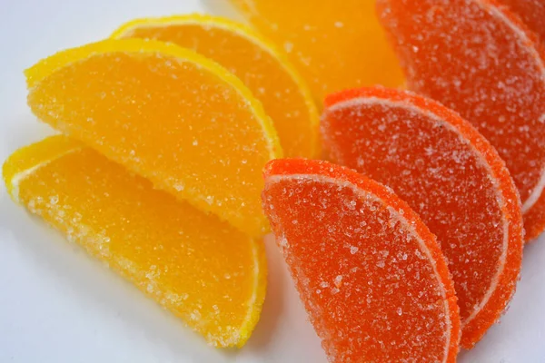 Yellow and orange jelly sweets made in the form of sliced orange slices, lemon, fruits located in plastic transparent containers and sprinkled with sugar.
