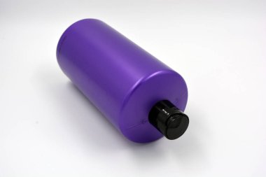 Beyaz arka planda siyah kapaklı büyük, mor bir plastik şampuan şişesi..