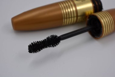 Dekoratif kozmetik ürünleri, kişisel bakım ürünleri, altın kaplamalı kadın siyah rimelleri, beyaz bir arka planda yer alıyor..