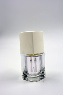 Beyaz kapaklı bir ahududu cam şişesinde kadın tırnağı cilası ve beyaz arka planda siyah bir fırça bulunur..