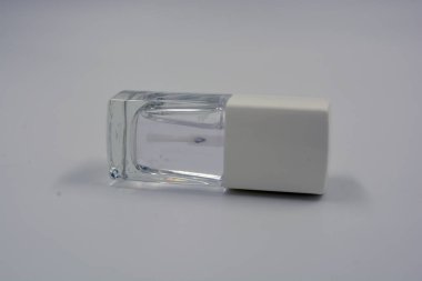 Beyaz kapaklı bir ahududu cam şişesinde kadın tırnağı cilası ve beyaz arka planda siyah bir fırça bulunur..