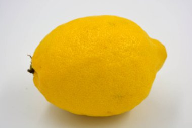 Lezzetli ve sağlıklı olgun meyveler, beyaz arka planda büyük sarı bir limon..