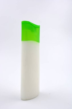 Kozmetik ürünleri, yüz kremi, yüz ve vücut bakımı şeffaf plastik bir şişede yeşil kapaklı beyaz arka planda yer almaktadır..