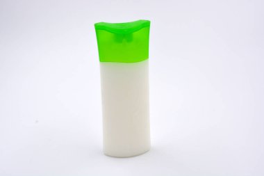 Kozmetik ürünleri, yüz kremi, yüz ve vücut bakımı şeffaf plastik bir şişede yeşil kapaklı beyaz arka planda yer almaktadır..