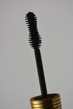 Dekoratif kozmetik ürünleri, kişisel bakım ürünleri, altın kaplamalı kadın siyah rimelleri, beyaz bir arka planda yer alıyor..