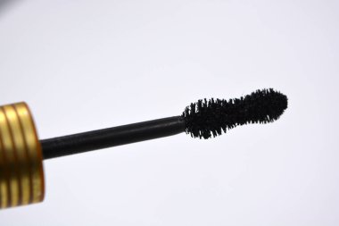 Dekoratif kozmetik ürünleri, kişisel bakım ürünleri, altın kaplamalı kadın siyah rimelleri, beyaz bir arka planda yer alıyor..